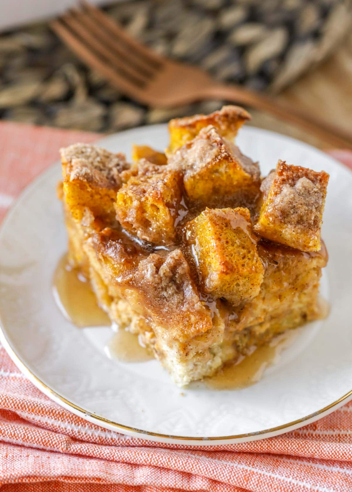 A white plate of pumpkin french toast bake topped with cinnamon buttermilk syrup