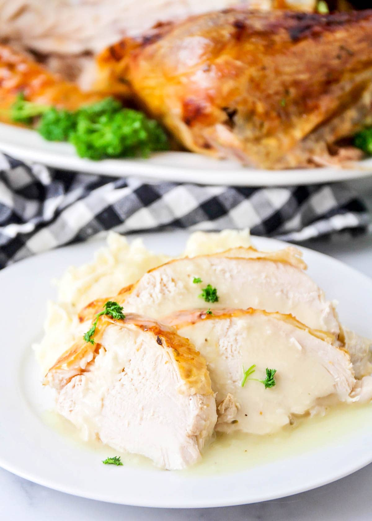 a plate of sliced turkey and mashed potatoes topped with turkey gravy.